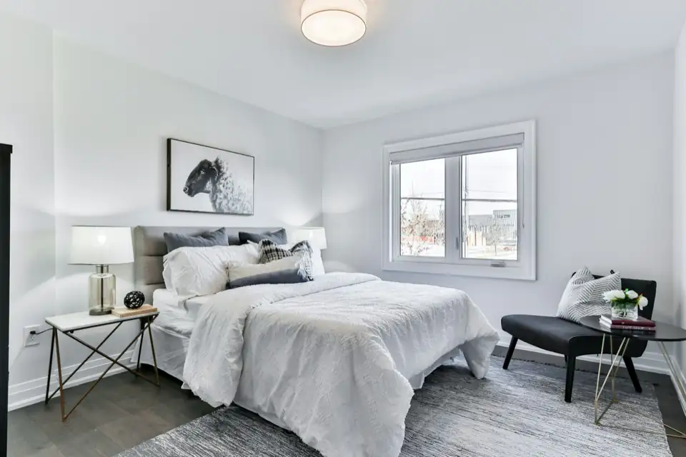 A calm, light bedroom with a made bed and a window.