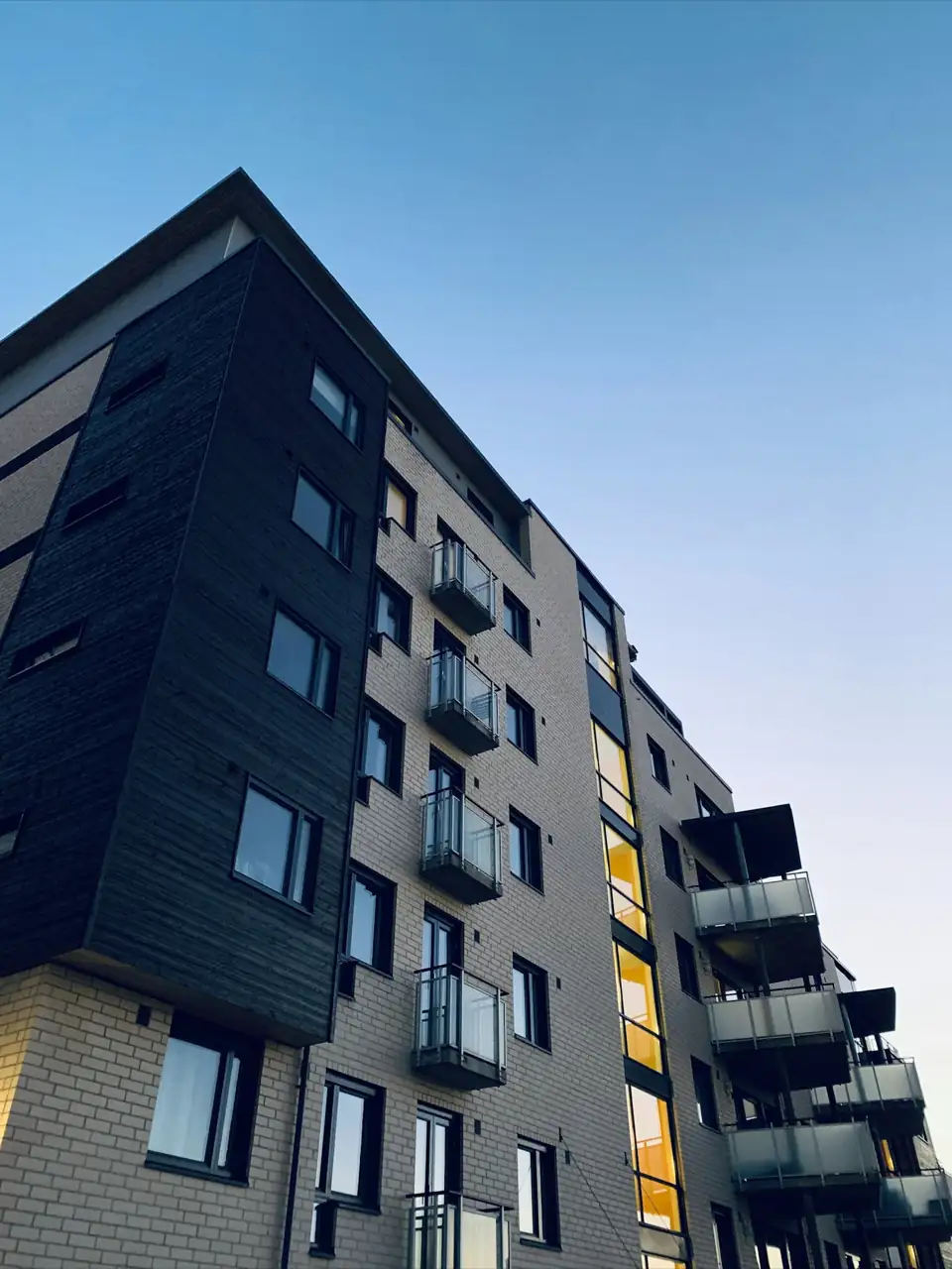 A modern apartment tower with balconies against a clear sky.