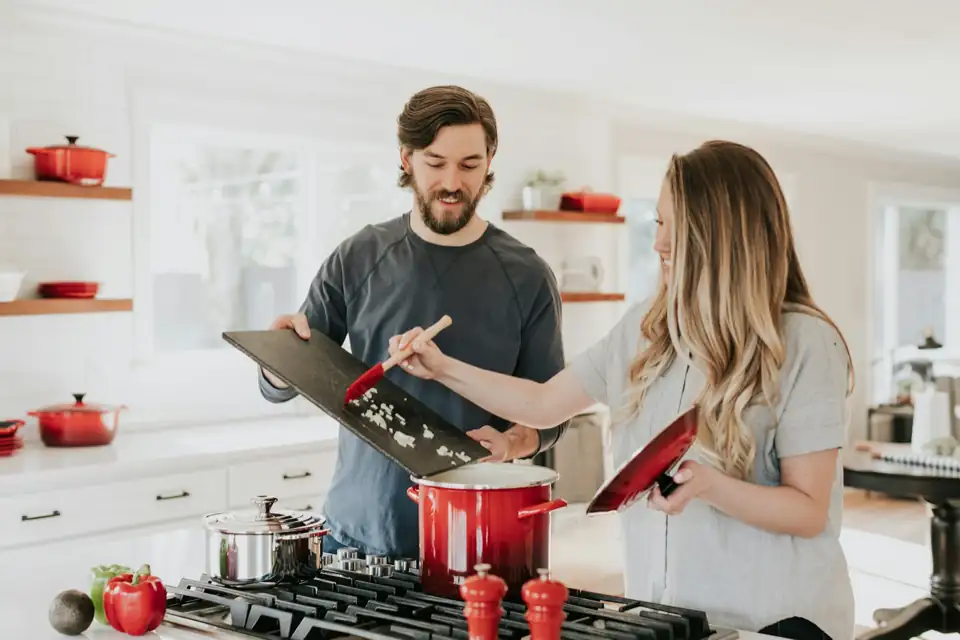 Residents cooking and talking together in a shared co-living kitchen.