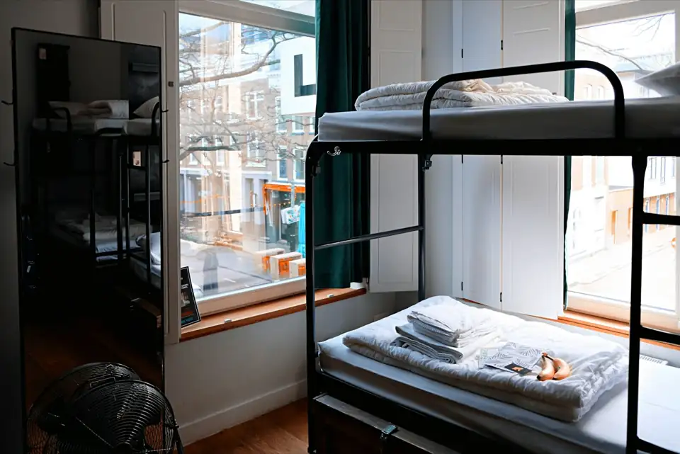 A hostel room with wooden bunk beds and lockers.